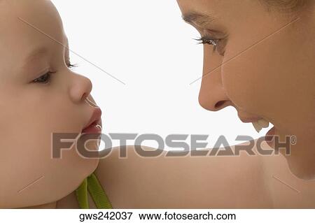 Close-up of a mid adult woman looking at her daughter and smiling View Large Photo Image Stock Photo - Close-up of a mid adult woman looking at her daughter and smiling. Fotosearch
