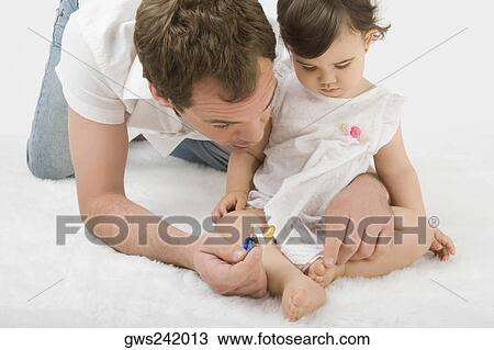 Stock Image - Close-up of a young man playing with his daughter. Fotosearch