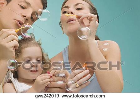 Mid adult couple blowing bubbles with their daughter View Large Photo Image Stock Photo - Mid adult couple blowing bubbles with their daughter. Fotosearch