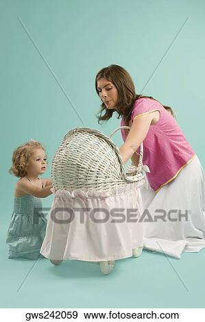 Mid adult woman looking at a baby carriage with her daughter View Large Photo Image Stock Photo - Mid adult woman looking at a baby carriage with her daughter. Fotosearch