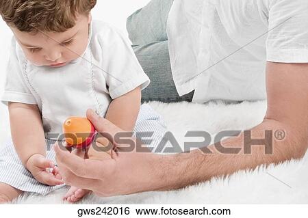 Stock Photograph - Mid section view of a young man playing with his son. Fotosearch