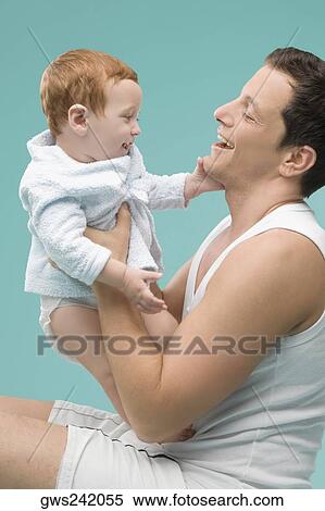 Stock Photography - Side profile of a mid adult man playing with his son. Fotosearch