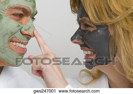 Stock Image - Close-up of a mature couple wearing facial masks and smiling. Fotosearch
