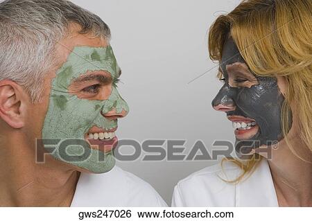 Stock Photograph - Close-up of a mature couple wearing facial masks and smiling. Fotosearch