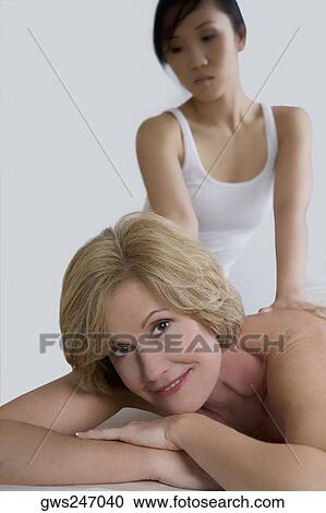 Stock Image - Close-up of a mature woman receiving a back massage from a massage therapist. Fotosearch