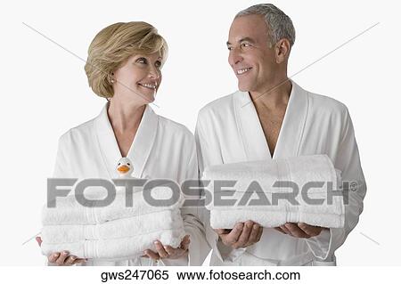 Stock Photography - Close-up of a senior man with a mature woman standing together and holding folded towels. Fotosearch