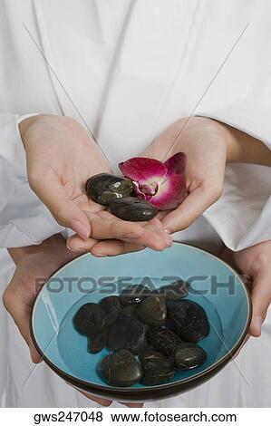 Stock Photo - Close-up of two people holding pebbles. Fotosearch