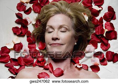 High angle view of a mature woman lying on a massage table with rose petals around her View Large Photo Image Stock Image - High angle view of a mature woman lying on a massage table with rose petals around her. Fotosearch