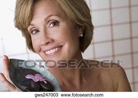 Portrait of a mature woman holding a bowl of pebbles and a flower View Large Photo Image Stock Image - Portrait of a mature woman holding a bowl of pebbles and a flower. Fotosearch