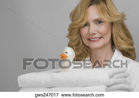 Stock Photo - Portrait of a mature woman holding folded towels and smiling. Fotosearch