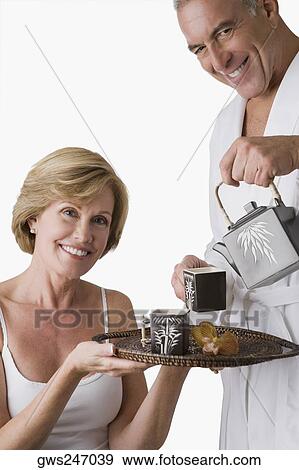 Portrait of a senior man pouring tea from a tea kettle into the cup with a mature woman holding a tray View Large Photo Image Stock Photo - Portrait of a senior man pouring tea from a tea kettle into the cup with a mature woman holding a tray. Fotosearch