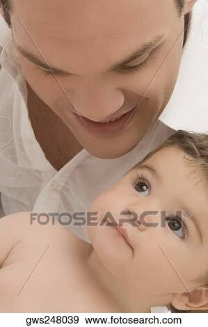 Close-up of a young man smiling with his son View Large Photo Image Stock Photo - Close-up of a young man smiling with his son. Fotosearch