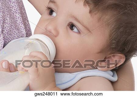 Stock Image - Mid section view of a woman feeding her son with a baby bottle. Fotosearch