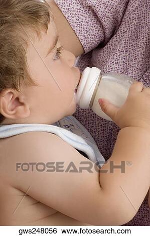 Mid section view of a woman feeding her son with a baby bottle View Large Photo Image Stock Photograph - Mid section view of a woman feeding her son with a baby bottle. Fotosearch