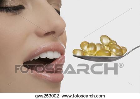 Close-up of a young woman having capsules from a spoon View Large Photo Image Stock Image - Close-up of a young woman having capsules from a spoon. Fotosearch