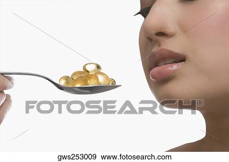 Close-up of a young woman holding a spoon of pills View Large Photo Image Stock Photo - Close-up of a young woman holding a spoon of pills. Fotosearch