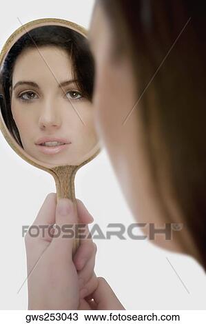 Close-up of a young woman looking at a mirror View Large Photo Image Stock Image - Close-up of a young woman looking at a mirror. Fotosearch