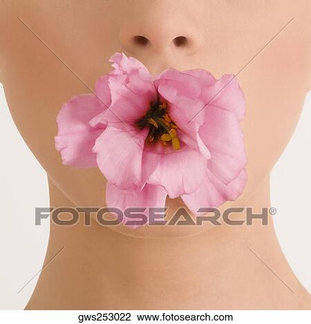 Stock Image - Close-up of a young woman with a flower in her mouth. Fotosearch