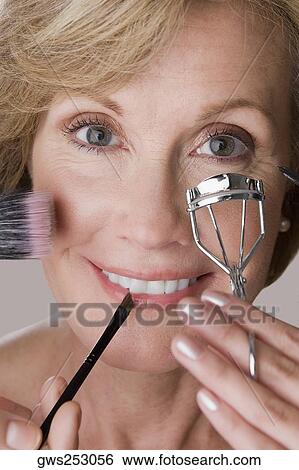 Portrait of a mature woman applying make-up on her face View Large Photo Image Stock Photograph - Portrait of a mature woman applying make-up on her face. Fotosearch