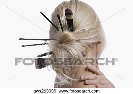 Rear view of a young woman with make-up brushes in her hair bun View Large Photo Image Stock Photograph - Rear view of a young woman with make-up brushes in her hair bun. Fotosearch