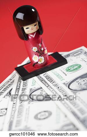 Stock Photograph - Close-up of a Chinese doll over US paper currency. Fotosearch