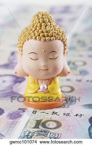 Close-up of a figurine of Buddha over Chinese currency View Large Photo Image Picture - Close-up of a figurine of Buddha over Chinese currency. Fotosearch