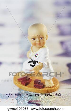 Stock Image - Close-up of a figurine over Chinese currency. Fotosearch