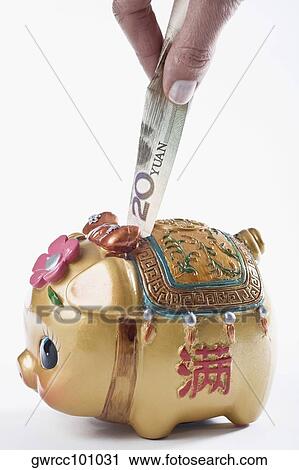 Close-up of a person's hand putting paper currency into a piggy bank View Large Photo Image Stock Image - Close-up of a person's hand putting paper currency into a piggy bank. Fotosearch