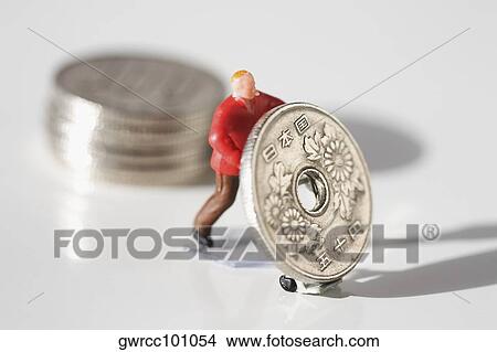 Figurine of a manual worker pushing a Chinese coin View Large Photo Image Picture - Figurine of a manual worker pushing a Chinese coin. Fotosearch