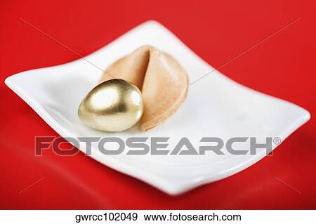 Stock Photo - Close-up of a golden egg with fortune cookie. Fotosearch