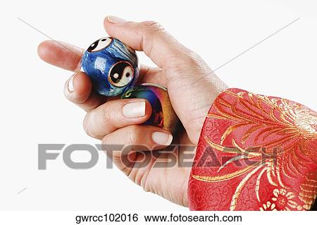 Stock Photograph - Close-up of a person's hand holding yin yang balls. Fotosearch