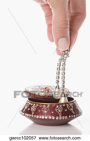 Close-up of a person's hand putting earring in a jewelry box View Large Photo Image Stock Photo - Close-up of a person's hand putting earring in a jewelry box. Fotosearch