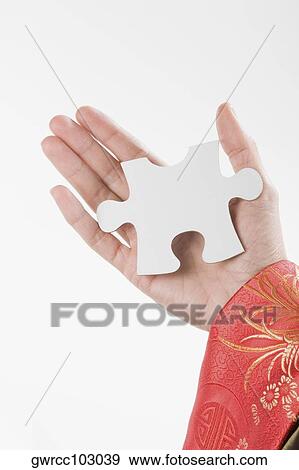 Close-up of a person's hand holding a piece of jigsaw puzzle View Large Photo Image Stock Photo - Close-up of a person's hand holding a piece of jigsaw puzzle. Fotosearch