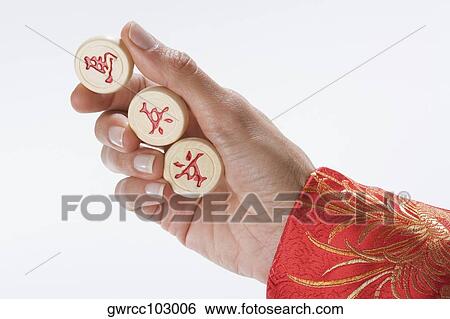 Stock Photograph - Close-up of a person's hand holding Chinese chess pieces. Fotosearch