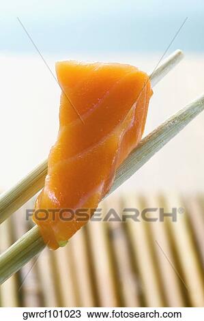 Stock Image - Close-up of sushi being held in chopsticks. Fotosearch