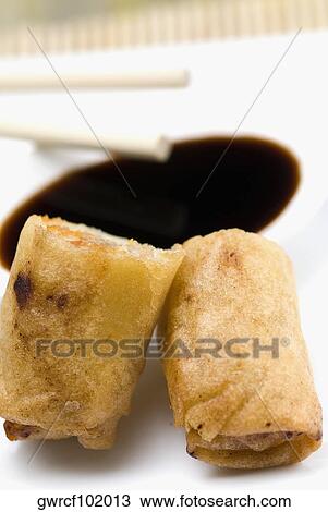 Stock Image - Close-up of spring rolls with a bowl of sauce. Fotosearch