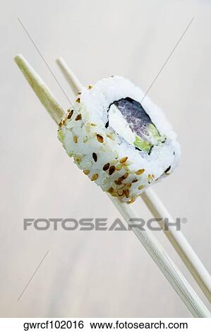Close-up of sushi being held in chopsticks View Large Photo Image Stock Photograph - Close-up of sushi being held in chopsticks. Fotosearch