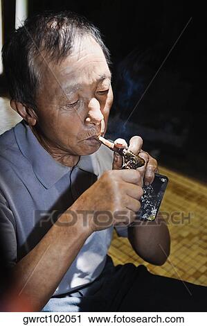 Close-up of a senior man lighting a cigar, Jinkeng Terraced Field, Guangxi Province, China View Large Photo Image Stock Image - Close-up of a senior man lighting a cigar, Jinkeng Terraced Field, Guangxi Province, China. Fotosearch