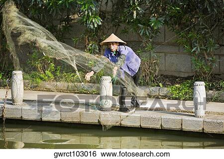 Stock Photograph - Fisherman throwing a fishing net in a lake, Guilin, Guangxi Province, China. Fotosearch