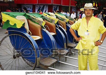 Stock Image - Portrait of a mid adult man standing near pedicabs, Nanjing, Jiangsu Province, China. Fotosearch