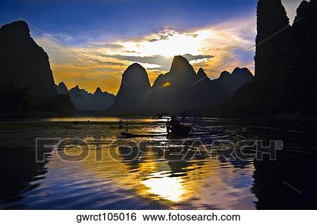 Stock Photograph - Fisherman fishing in a river with a hill range in the background, Guilin Hills, XingPing, Yangshuo, Guangxi Province, China. Fotosearch