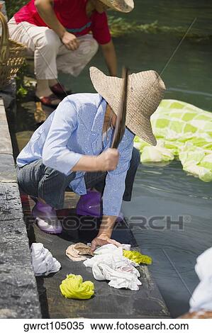 Stock Photography - Woman washing clothes at riverside, Xidi, Anhui Province, China. Fotosearch