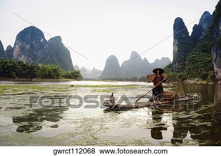 Fisherman on a bamboo raft with a hill range in the background, Guilin Hills, XingPing, Yangshuo, Guangxi Province, China View Large Photo Image Stock Photo - Fisherman on a bamboo raft with a hill range in the background, Guilin Hills, XingPing, Yangshuo, Guangxi Province, China. Fotosearch