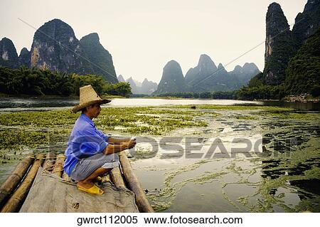 Side profile of a mature man crouching on a bamboo raft with a hill range in the background, Guilin Hills, XingPing, Yangshuo, Guangxi Province, China View Large Photo Image Stock Photography - Side profile of a mature man crouching on a bamboo raft with a hill range in the background, Guilin Hills, XingPing, Yangshuo, Guangxi Province, China. Fotosearch