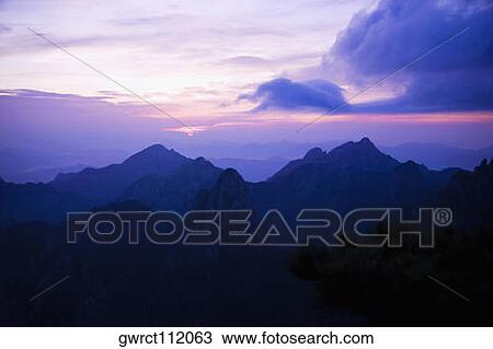 Stock Image - Silhouette of a mountain range at dusk, Huangshan Mountains, Anhui Province, China. Fotosearch