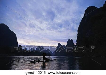 Stock Photography - Silhouette of a person in a river with a hill range in the background, Guilin Hills, XingPing, Yangshuo, Guangxi Province, China. Fotosearch