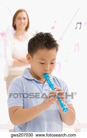 Close-up of a schoolboy playing a flute with his female teacher standing in the background View Large Photo Image Stock Image - Close-up of a schoolboy playing a flute with his female teacher standing in the background. Fotosearch