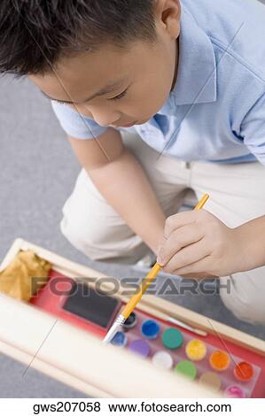 Stock Photo - High angle view of a schoolboy painting in an art class. Fotosearch