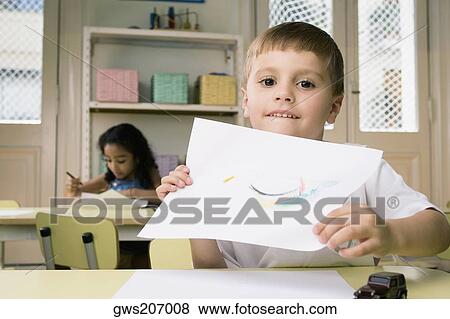 Portrait of a boy showing a drawing with a girl drawing in the background View Large Photo Image Stock Photo - Portrait of a boy showing a drawing with a girl drawing in the background. Fotosearch
