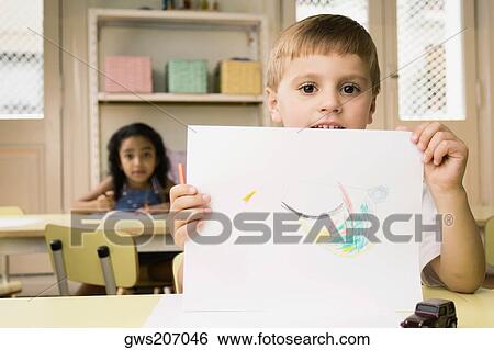 Portrait of a boy showing a drawing with a girl drawing in the background View Large Photo Image Stock Photograph - Portrait of a boy showing a drawing with a girl drawing in the background. Fotosearch